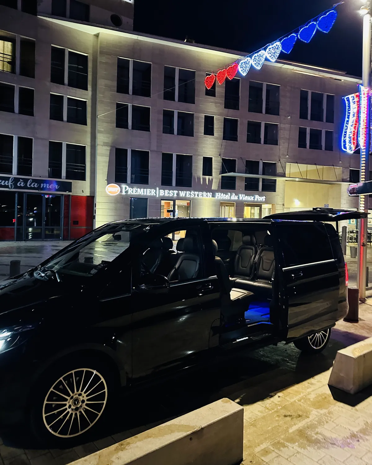 Mercedes Classe V Prestige VTC portes ouvertes devant un hôtel, de nuit
