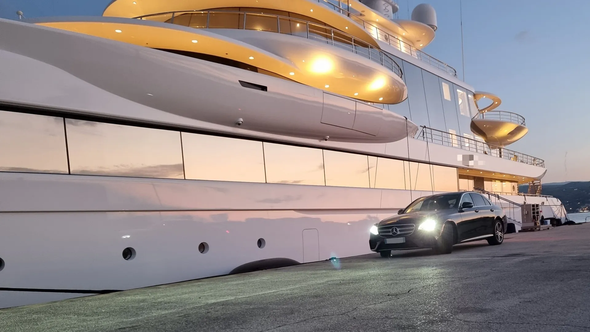 Mercedes Classe E Prestige VTC sur le quai au pied d'un superyacht, au coucher du soleil