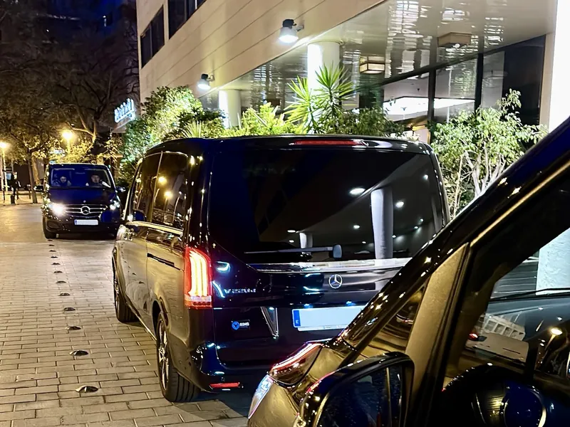 Plusieurs vans Mercedes Prestige VTC devant l'entrée d'un hôtel, de nuit
